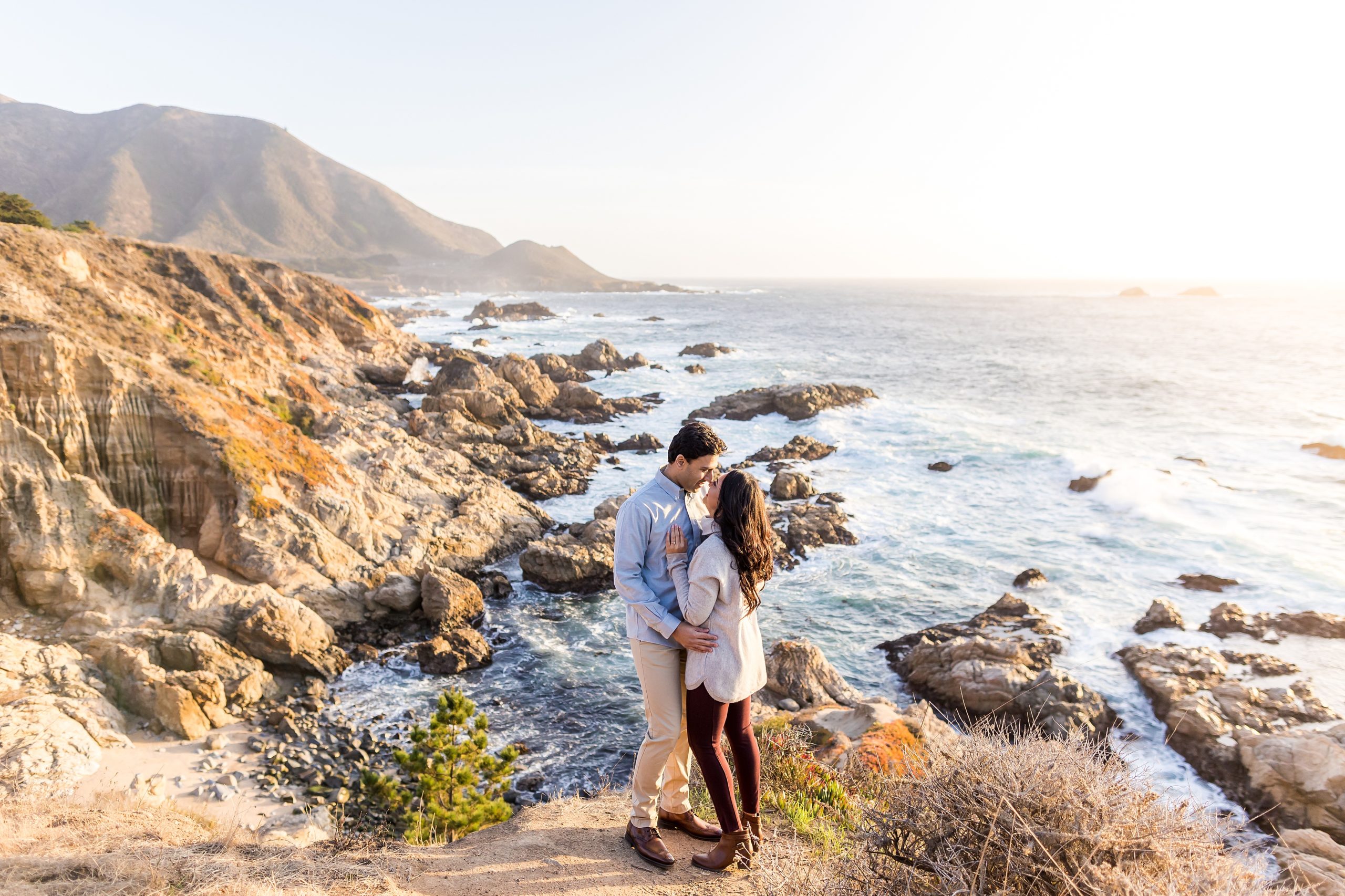 A couple embracing during their engagement session on the cliffs of Big Sur photographed by Shannon Cronin